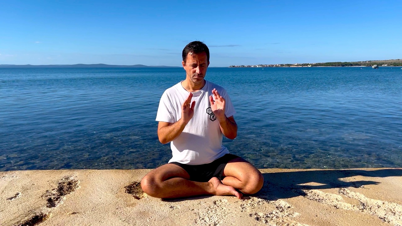 Danijel Salijević prakticira reiki meditaciju u sjedećem položaju na plaži.